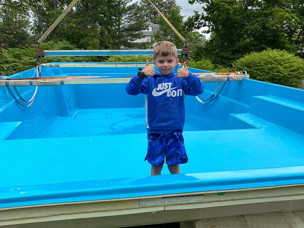 boy standing in the pool with thumbs up